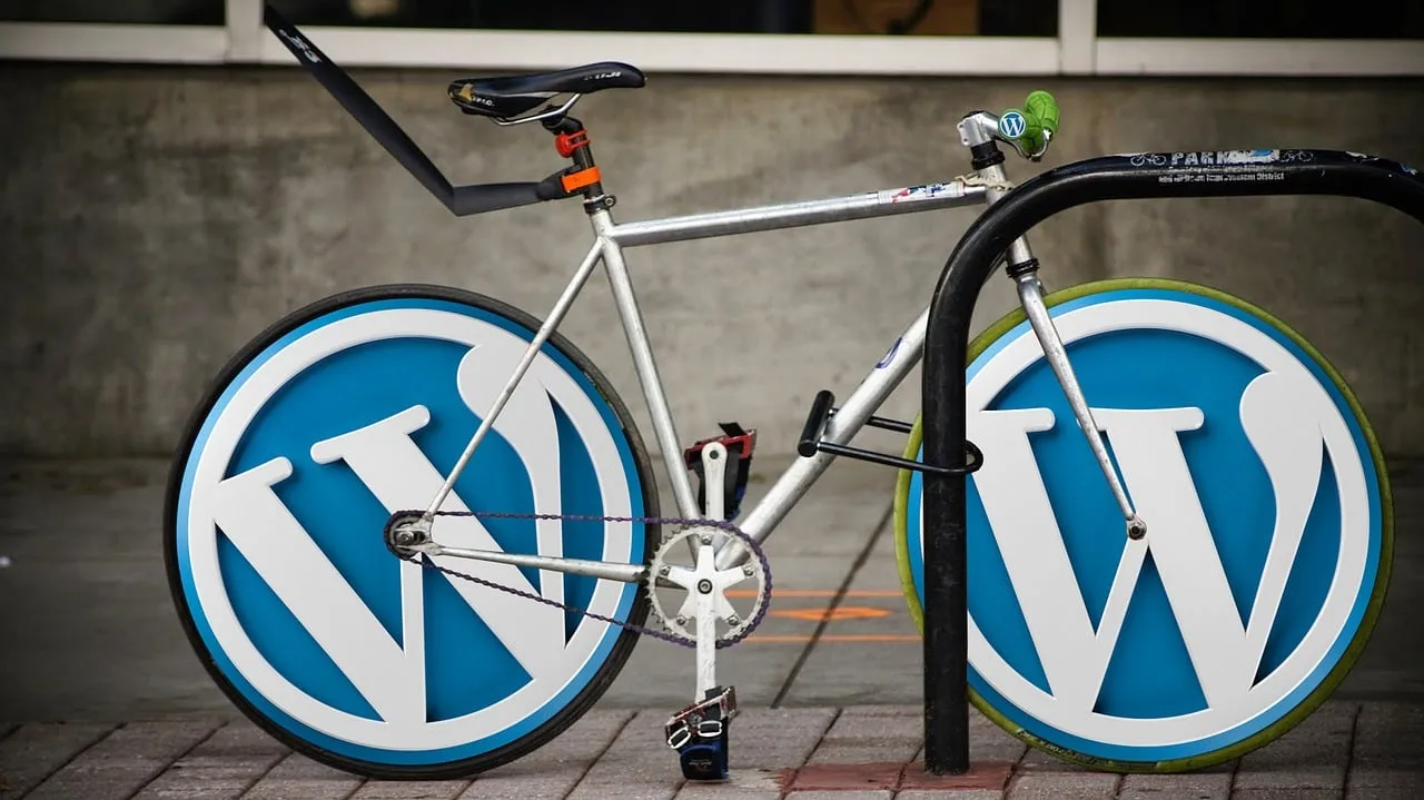 Uma bicicleta está estacionada em um bicicletário, suas rodas substituídas por grandes logotipos do WordPress, combinando o design da bicicleta com o reconhecível símbolo W azul e branco — uma homenagem criativa à otimização do WordPress.